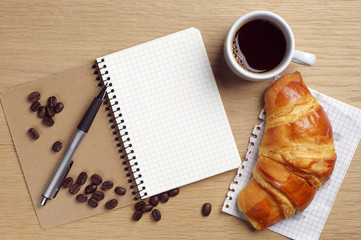 Opened notebook, croissant and coffee