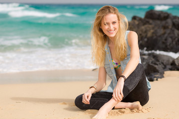 Blondes Mädchen sitzt am Strand