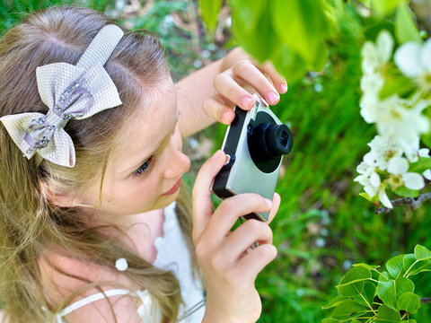 Girl photographs blossoming tree.