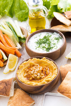 hummus in wooden bowl with pita bread and fresh vegetables