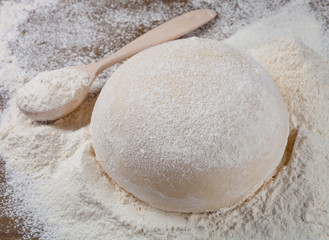 Fototapeta na wymiar Fresh dough and a wooden spoon with flour