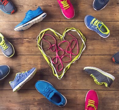Various running shoes land shoelaces heart on wooden background