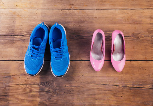 Running shoes and pink court shoes on a wooden floor background