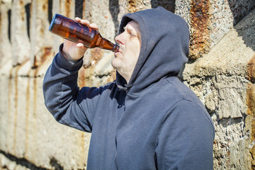 Men with bottle of alcohol near wall