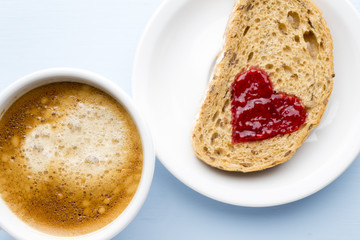 Fresh coffee. Grain slice of bread with jam heart shape.