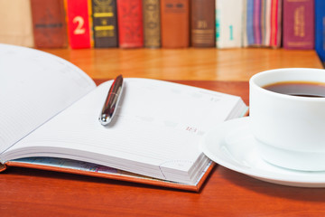 Diary on the desk and a cup of coffee