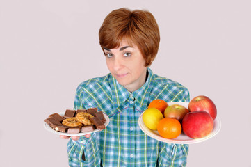 Woman holding plates with fruit and sweets