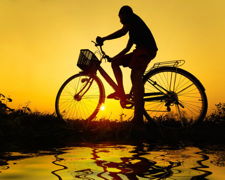 silhouette of bicycle with man at sunset