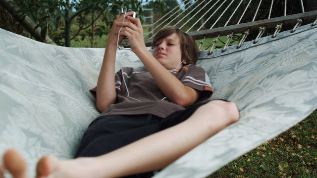 boy in a hammock listening to an iPod