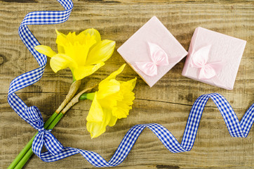 Gift boxes with yellow flower and ribbon on wooden background