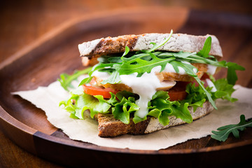 Rye toast sandwich with green leaf, tomato and chicken