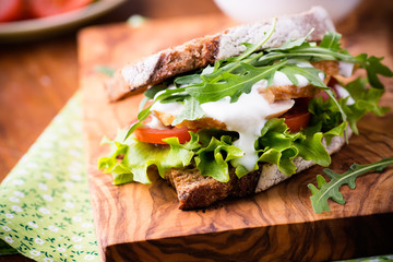 Rye toast sandwich with green leaf, tomato and chicken