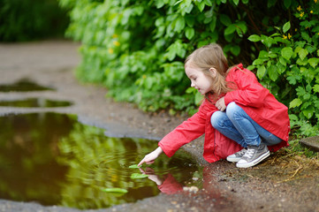 Adorable girl playing in a puddle on rainy day