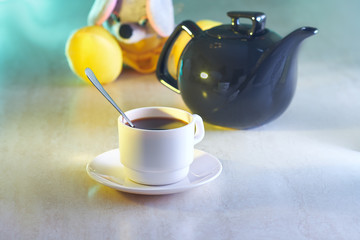 Coffee cup and kettle with toy on table
