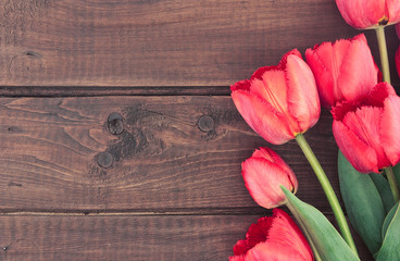 Bouquet of red tulips on wooden background with space for text