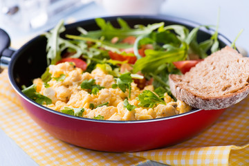 Scrambled eggs with fresh salad in frying pan