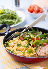 Scrambled eggs with fresh salad in frying pan