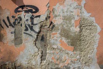 Muro vecchio con graffi e scritte, intonaco danneggiato