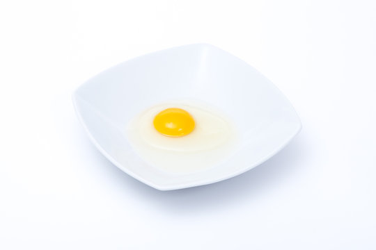 uovo crudo in un piatto bianco su sfondo bianco