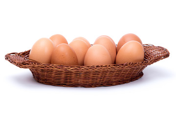 Wicker basket full of eggs on white background