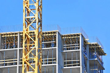 Crane and building construction site against blue sky