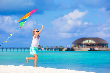 Obraz na płótnie Canvas Little happy girl playing with flying kite on tropical beach