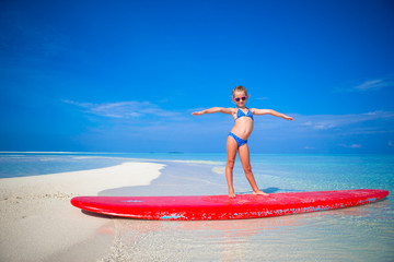 Little adorable girl practice surfing position at beach