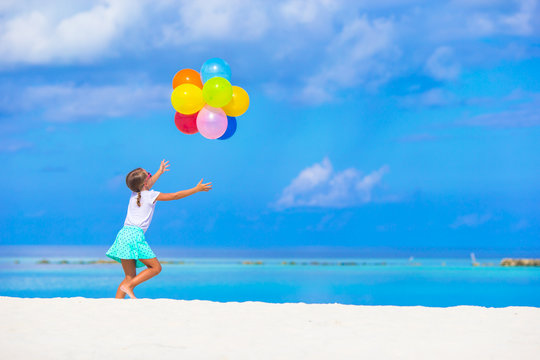 Adorable little girl playing with balloons at the beach