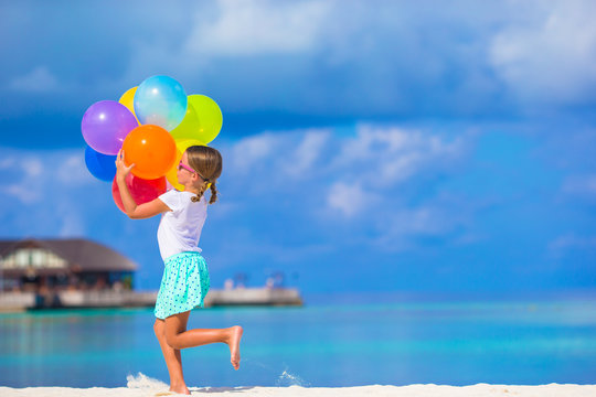Cute little girl playing with balloons at the beach