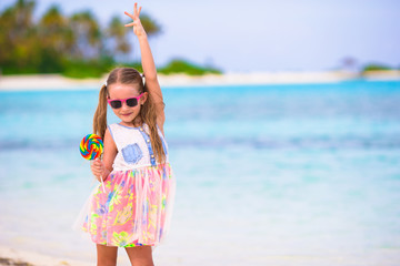 Adorable little girl have fun with lollipop on the beach