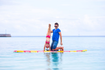 Little girl and young dad have fun on surfboard