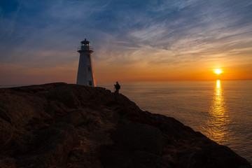 Photographer at Lighthouse at Ocean Sunrise Orange Horizon Blue Skies