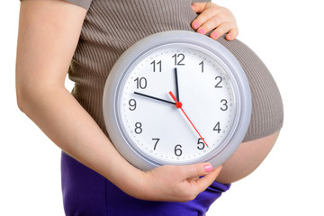 Pregnant woman with big belly holding clock. It's time concept.
