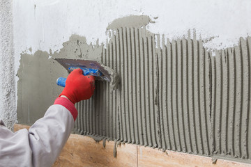 Obraz na płótnie Canvas Ceramic Tiles. Tilerman hand spreading adhesive material