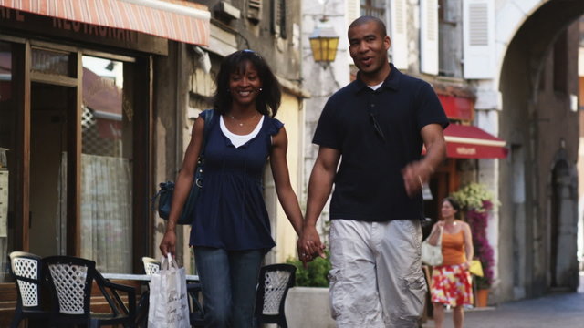 couple walking down a European street holding hands and window shopping
