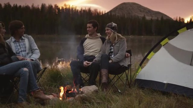 MS PAN Four people sitting by camp fire on edge of lake at sunset, Uinta Mountains, Utah, USA