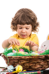 Toddler boy arrange Easter eggs in basket