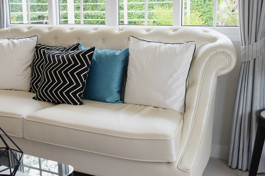 white and blue pillows on a white leather couch in vintage livin