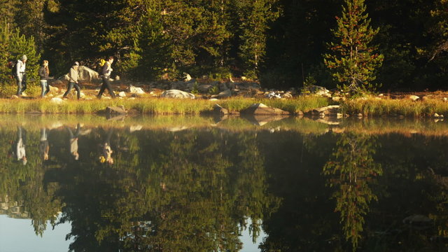 WS Four hikers walking along lake's edge, Uinta Mountains, Utah, USA