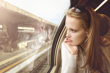 Naklejka na ściany i meble Pensive young girl on the train at the station