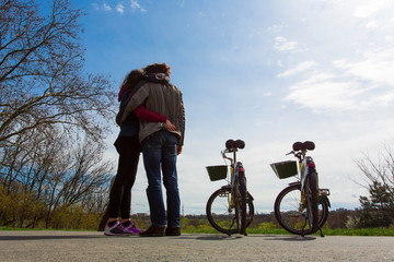Couple holding each other with the bicycles and two, blue sky an