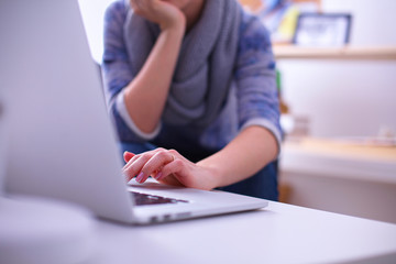 Fototapeta premium Woman working with a laptop sitting at the desk