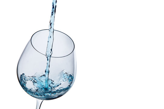 Water is poured in a glass on a white background