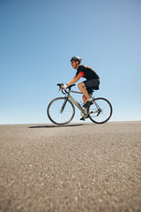 Fototapeta premium Male cyclist riding bicycle on flat road