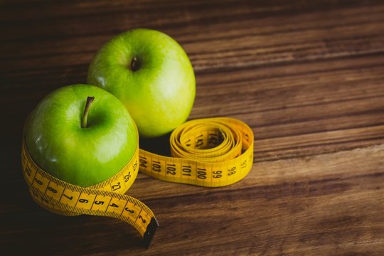 Green apples with measuring tape