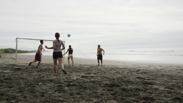 Wide slow motion panning shot of people playing soccer on beach / Esterillos, Puntarenas, Costa Rica