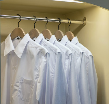 Row Of White Shirts Hanging On Coat Hanger In Wardrobe