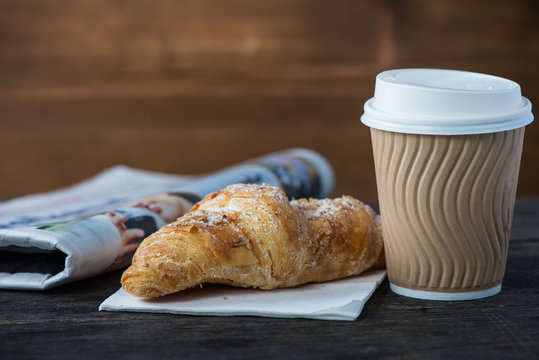 Take away coffee and fresh croissant and newspaper