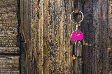 Pink key hanging on rustic nail