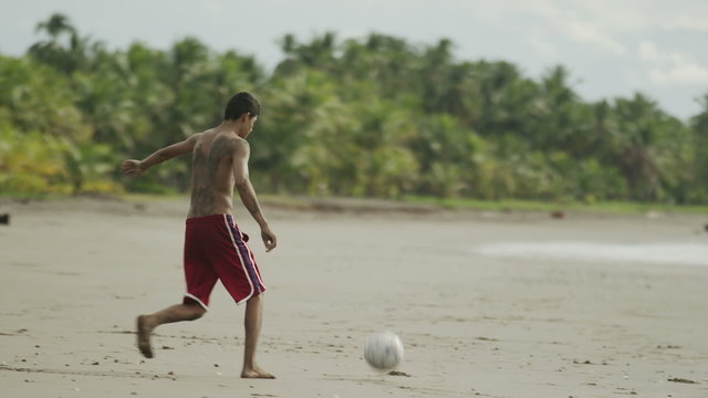 Wide panning slow motion shot of people playing with soccer ball on beach / Esterillos, Puntarenas, Costa Rica